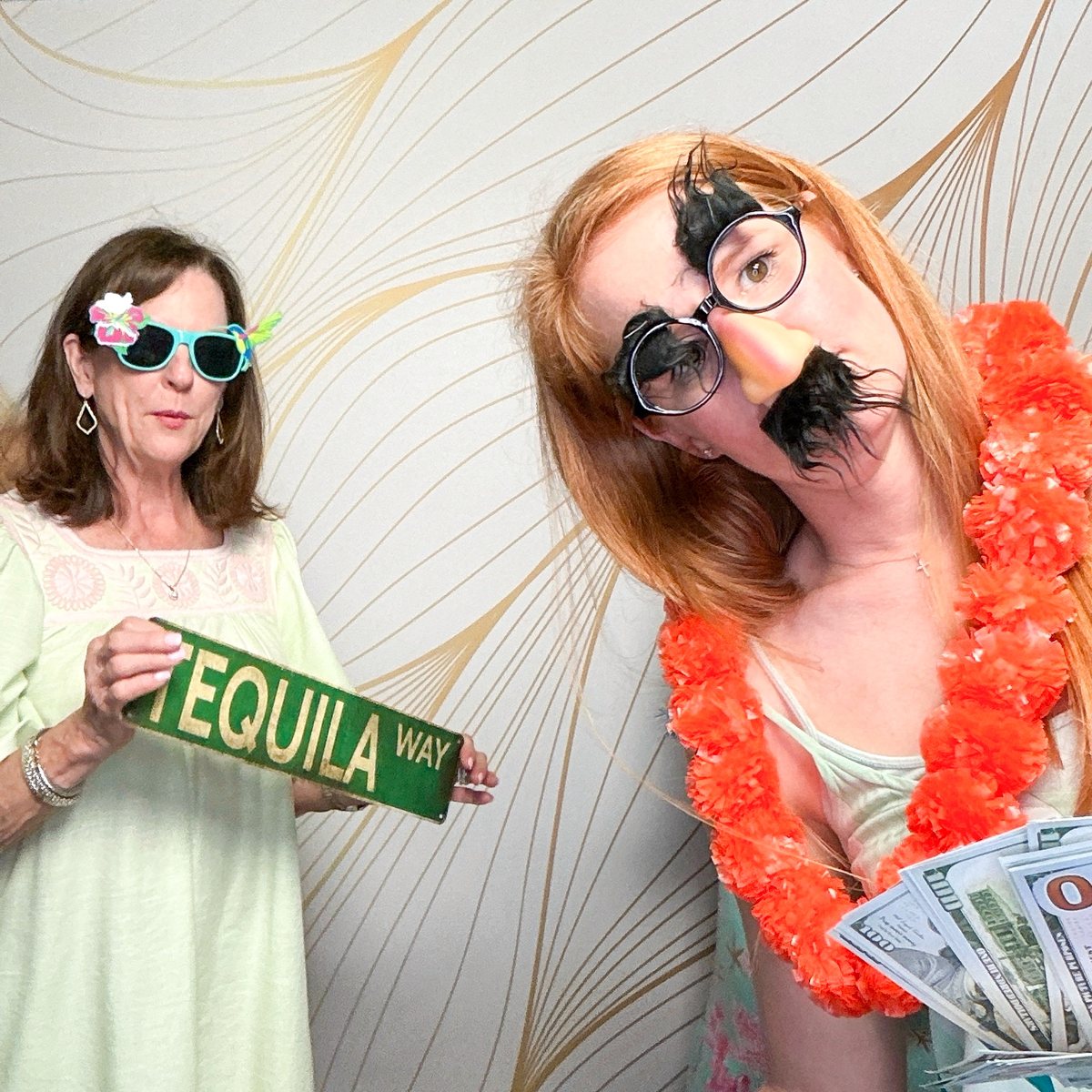 Two guests with props, a Tequila Way sign and a lei, at a Galveston birthday party photo booth