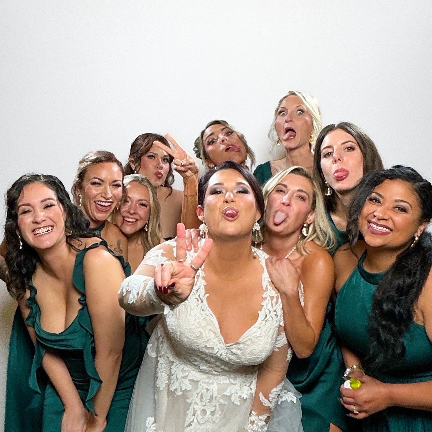 Bride and bridesmaids in green making faces in the photo booth at a Galveston wedding